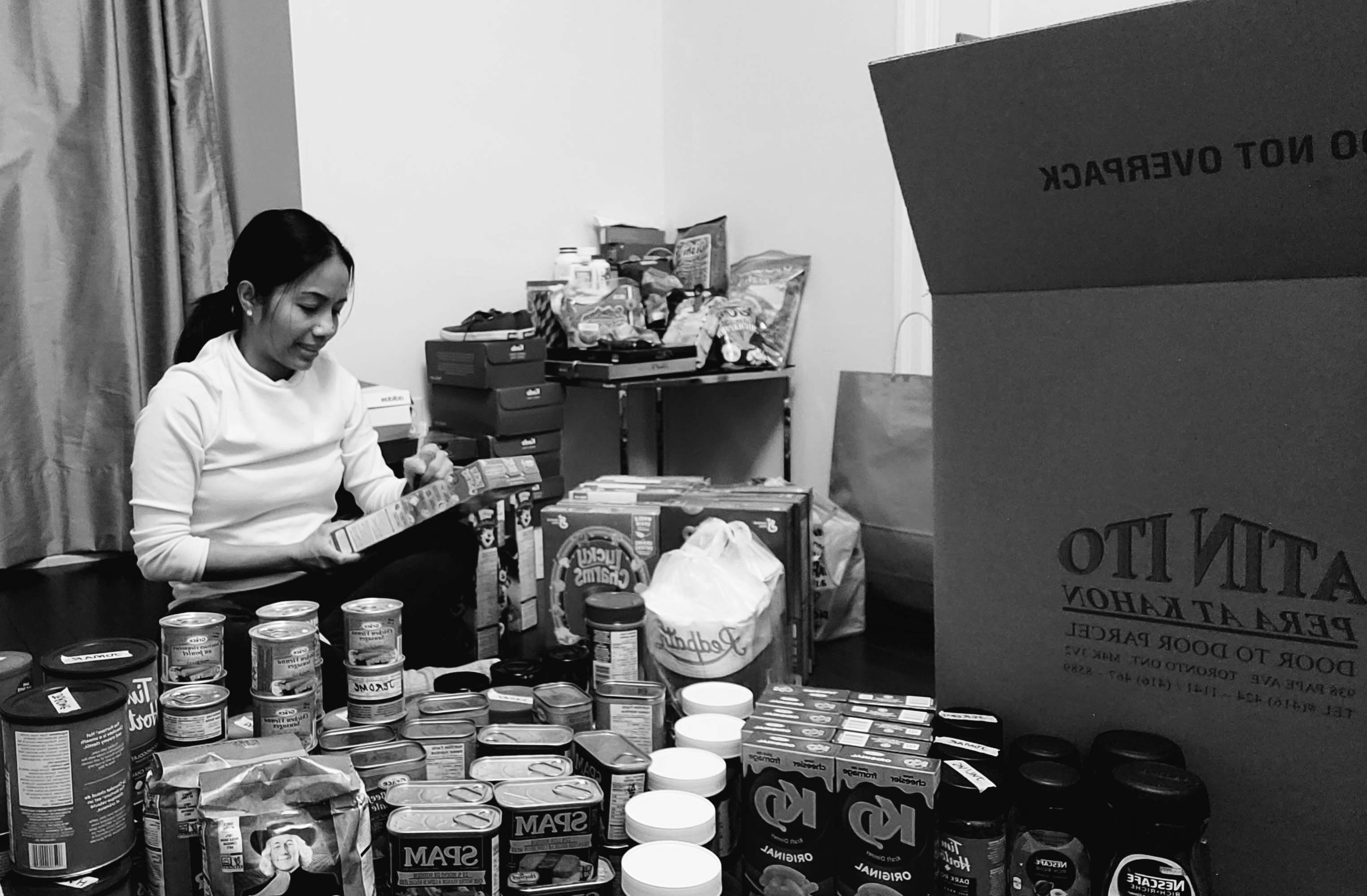Woman packing food (cans, boxes etc) into a box